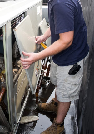 An HVAC heating ventilating air conditioning technician working on a large commercial unit.